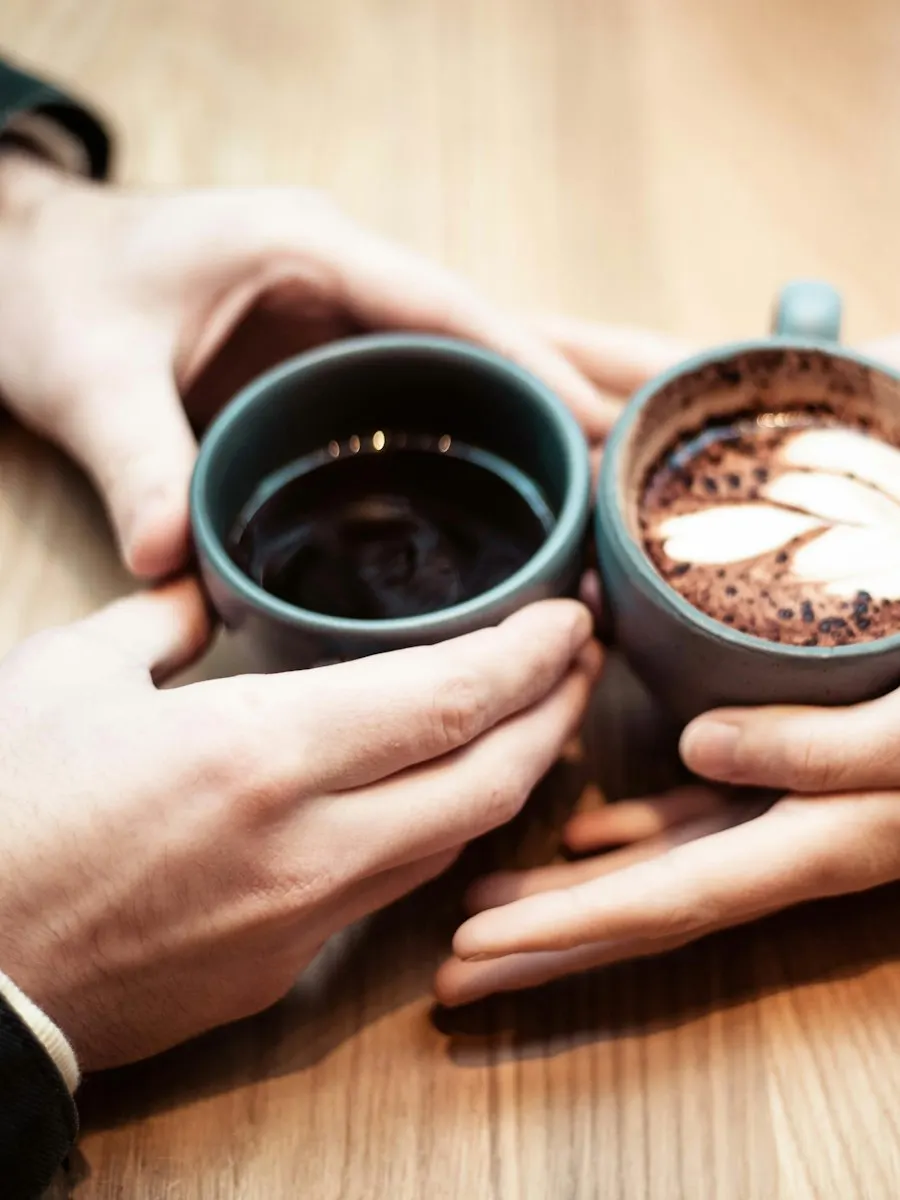 Two people raising coffee cups across a table