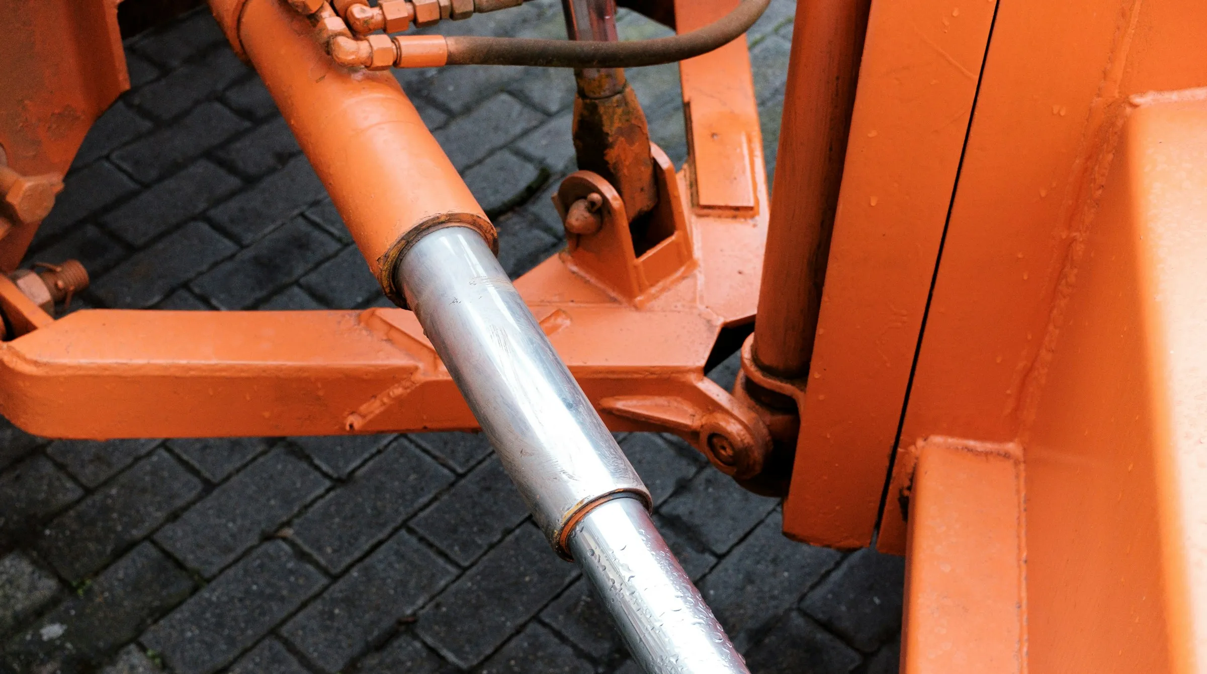 A chrome cylinder rod extending from an orange machine frame