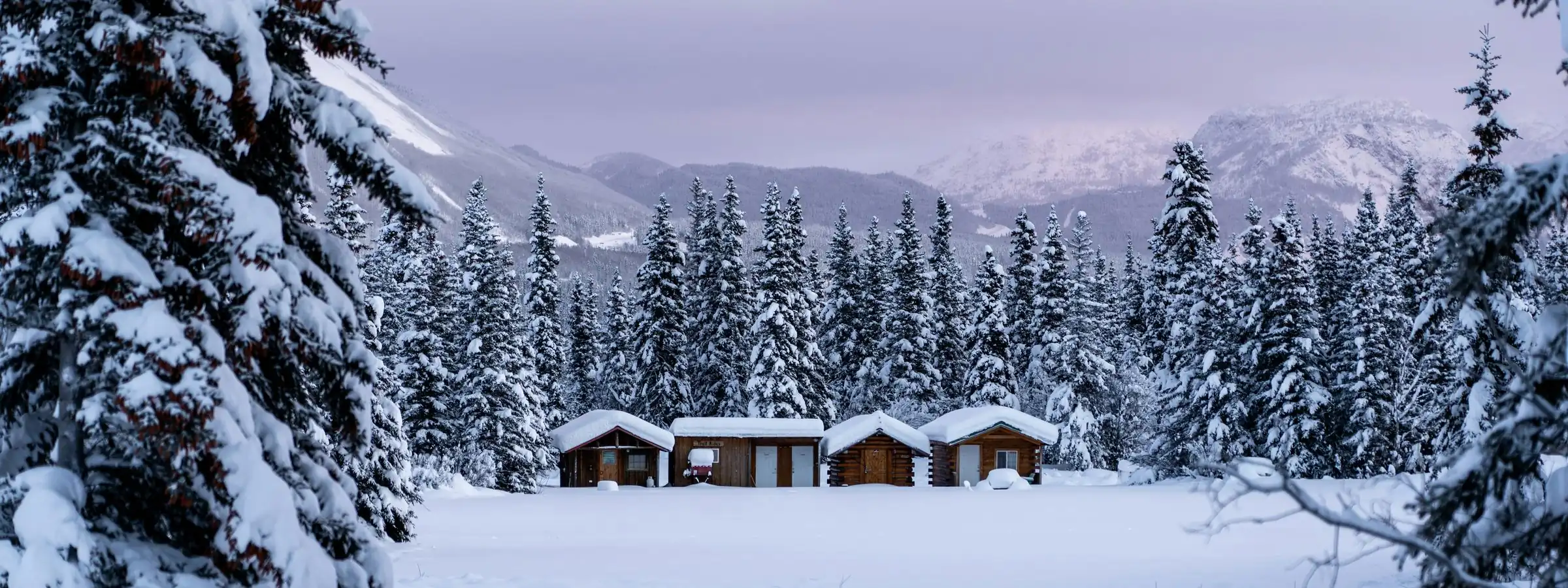 Timber cabins at the edge of a misty lake at dusk