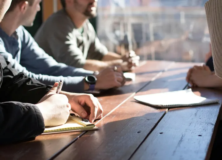 Colleagues taking notes around a table