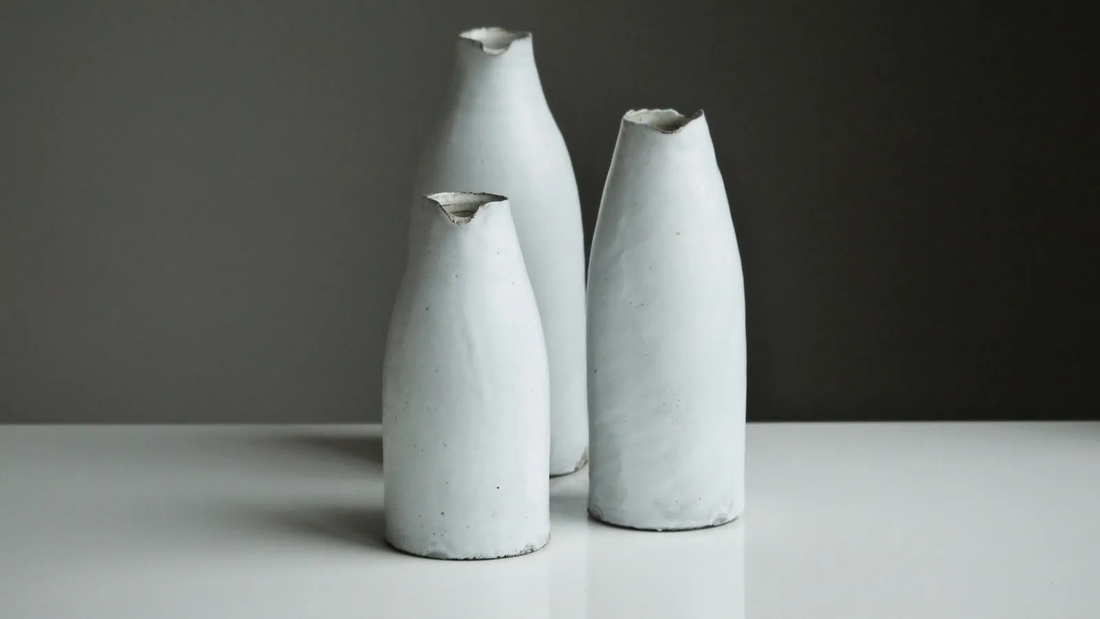 Three white ceramic vases on a table