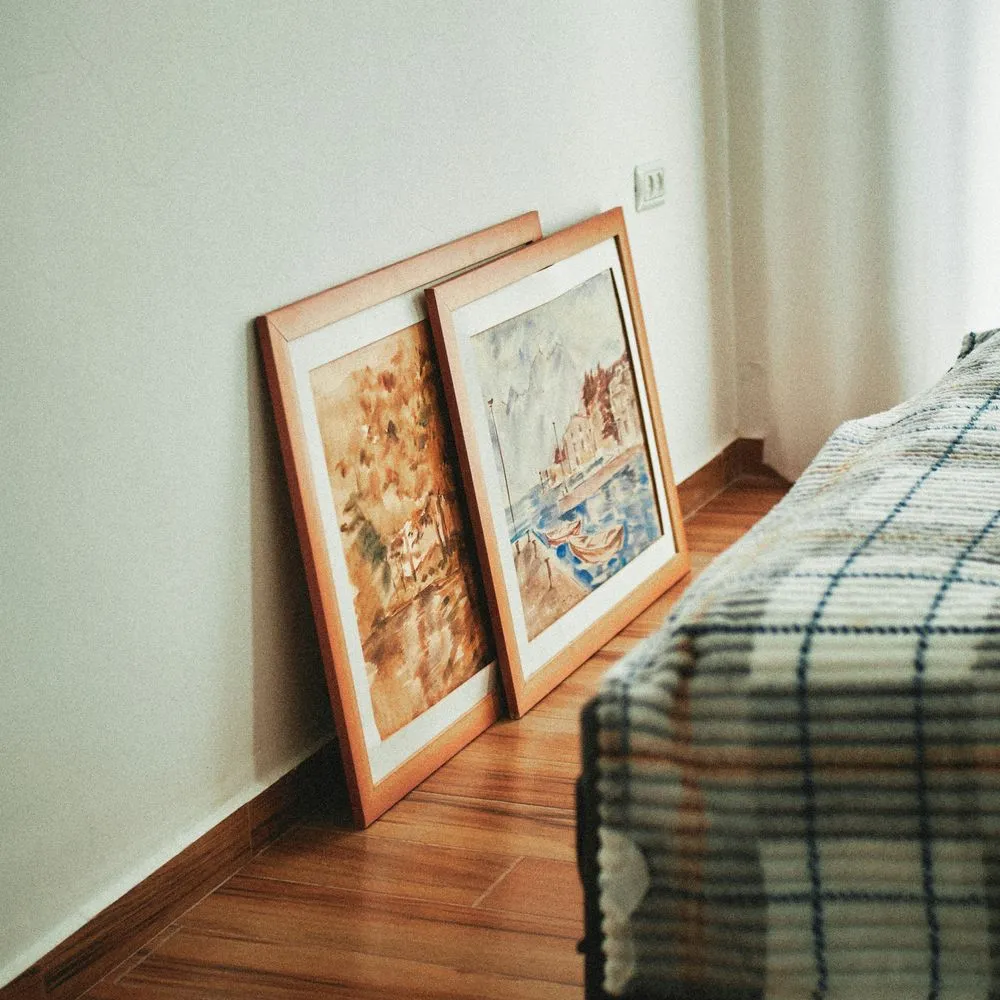 Framed prints stacked and leaning against a white wall